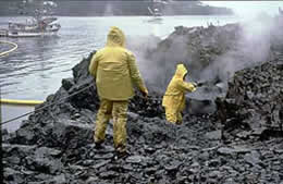 Workers spray beach rocks with hot water to remove oil.